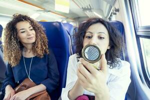 dos sonriente encantador muchachas mientras ellos maquillaje sentado en un carro tren foto