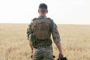 Soldier man standing against a field photo