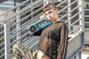 joven hembra cantante rap caucásico tatuado posando con un radio foto