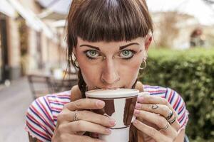 young woman with blue eyes gets her lips dirty with cream photo