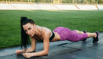 Slim athletic woman with dumbbells in the stadium photo