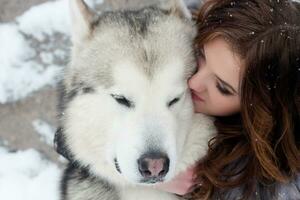joven mujer con lobo perro en nieve foto