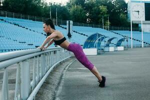 Slim athletic woman with dumbbells in the stadium photo