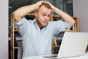 young businessman at his desk looking fearfully photo