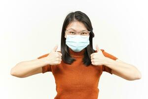 Wearing Mask and Showing Thumbs Up Of Beautiful Asian Woman Isolated On White Background photo