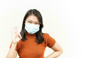 Wearing Medical Mask And Showing Ok Sign Of Beautiful Asian Woman Isolated On White Background photo