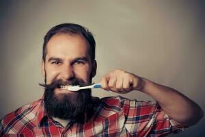 hombre Lavado su dientes en frente de el espejo foto