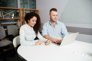 Two Serious Young Business People Sitting Table with Laptop photo