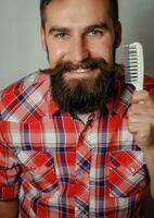 young man comb his beard and moustache  gray background photo