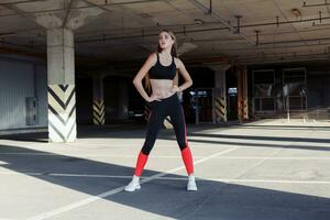 Relaxed young sportswoman standing outdoors and smiling. photo