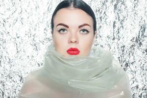 Young beautiful girl in a black dress on a silver background. photo