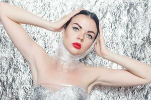 Young beautiful girl in a black dress on a silver background. photo