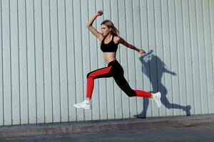 Full length of healthy female exercising and jumping outdoors. photo