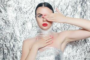 Young beautiful girl in a black dress on a silver background. photo