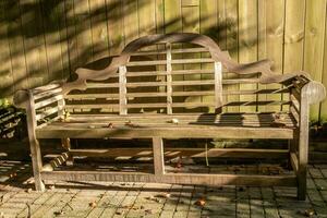 wooden bench in front of wooden fence light and shade photo