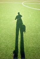 fútbol campo en césped con humano sombra foto