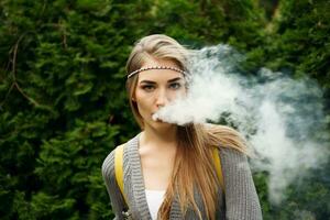 Happy vaping young white blonde girl photo