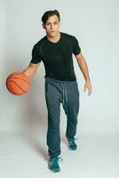 Handsome young smiling man carrying a basketball ball photo