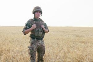 Soldier man standing against a field photo