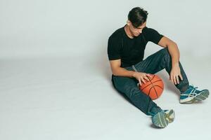 Handsome young smiling man carrying a basketball ball photo