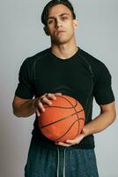 hermoso joven sonriente hombre que lleva un baloncesto pelota foto