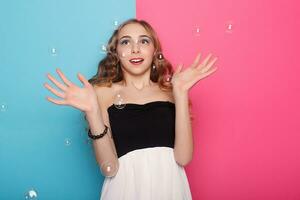 Beautiful young woman with soap bubbles over cyan background photo