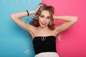 Beautiful young woman with soap bubbles over cyan background photo