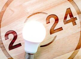 Happy new year 2024, 3d earth orb with digital world map placed on white block stack with 2024 year numbers with searching icon and rising arrow, trend growth graph on blue background. photo