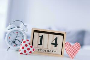 Valentines day concept. Hand make yarn red heart beside wooden block calendar set on Valentines date 14 February on table and bright room background. Happy valentine day. photo