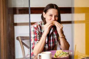 Woman making funny face while eating breakfast in cafe. photo