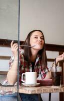 mujer haciendo gracioso cara mientras comiendo desayuno en cafetería. foto