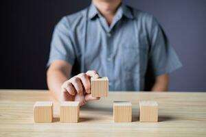 hand of a businessman hold wood empty five blocks with copy space for text or symbols, development concept for growth success process. photo