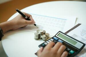 Businessman Saving money analyzing investment charts and pressing calculator buttons over documents. Accounting Concept photo