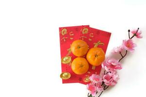 Top view of the Mandarin orange on red envelopes and gold ingot decorated with plum blossom isolated on white background. Copy space for text. Chinese New Year festival concept. photo