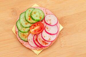 crujiente galleta emparedado con Fresco pepino, queso, embutido, rábano y tomate en corte tablero. fácil desayuno. rápido y sano sándwiches pan crujiente con sabroso relleno. sano dietético bocadillo foto