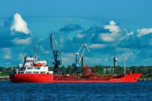 Red cargo tanker ship moving by the river photo