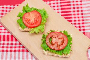 Rice Cake Sandwiches with Tomato and Lettuce on Wooden Cutting Board. Easy Breakfast. Diet Food. Quick and Healthy Sandwiches. Crispbread with Tasty Filling. Healthy Dietary Snack photo
