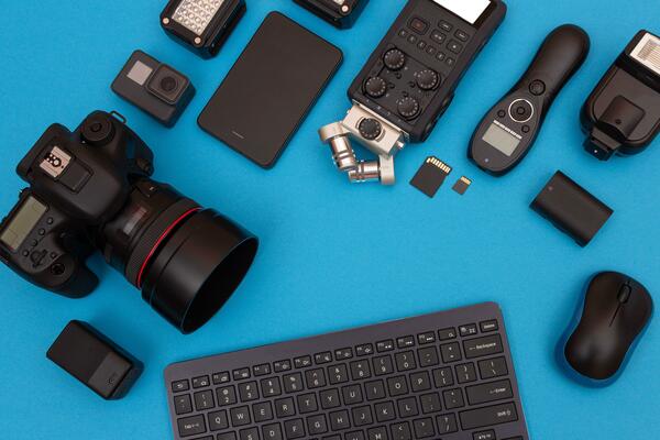 Top View of Photographer's, Videographer's or Video Blogger's Workplace. Digital Gadgets Lying on Blue Table Flat Lay