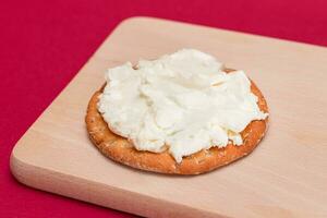 Crispy Cracker Sandwich with Cream Cheese on Wooden Cooking Board on Magenta Background photo