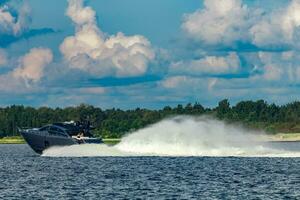 Grey speedboat moving fast by the river in Latvia. Water sport photo