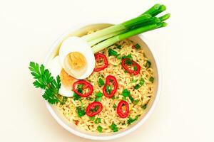 Beautiful Noodle Dish with Green Onions, Eggs, Red Hot Pepper and Greens on White Background. Instant Noodles Top View photo