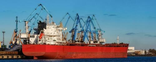 Red cargo ship loading in the port of Riga, Europe photo