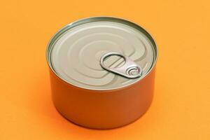 Unopened Tin Can with Blank Edge on Orange Background. Canned Food. Aluminum Can for Safe and Long Term Storage of Food. Steel Sealed Food Storage Container photo