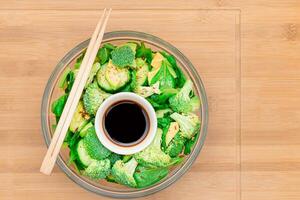 Fresh Green Salad of Avocado, Broccoli, Spinach and Cucumber for Detox with Soy Sauce on Wooden Cutting Board. Vegan Salad. Vegetarian Culture. Raw Food. Healthy Eating and Vegetable Diet photo