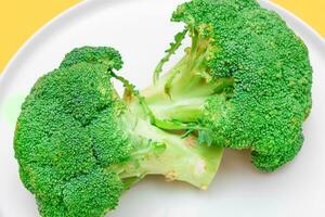 Two Fresh and Raw Pieces of Broccoli on White Plate. Uncooked Green Cabbage. Vegan and Vegetarian Culture. Raw Food. Healthy Eating and Vegetable Diet photo