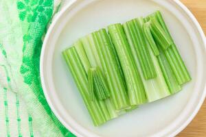 Fresh Chopped Celery Sticks with Water Drops in White Bowl Top View. Vegan and Vegetarian Culture. Raw Food. Healthy Diet with Negative Calorie Content photo