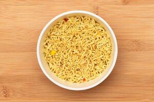 Instant Noodles in Disposable Cup on Wooden Background Top View. Asian Fast Food. Quick Lunch photo