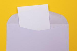 Violeta sobre con blanco blanco sábana de papel adentro, acostado en amarillo antecedentes burlarse de arriba con Copiar espacio. recepción correo o aviso, enviando tarjeta postal parte superior vista, plano laico foto