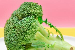 Fresh and Raw Broccoli Against the Pink Background. Uncooked Green Cabbage. Vegan and Vegetarian Culture. Raw Food. Healthy Eating and Vegetable Diet photo