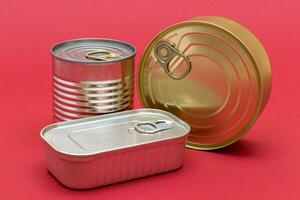 A Group of Stacked Tin Cans with Blank Edges on Red Background. Canned Food. Different Aluminum Cans for Safe and Long Term Storage of Food. Steel Sealed Food Storage Containers photo